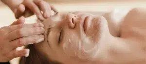 Woman receiving facial cleansing treatment at spa