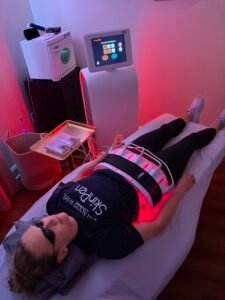 Person receiving red light therapy treatment on abdomen