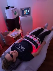 Person receiving red light therapy treatment on abdomen