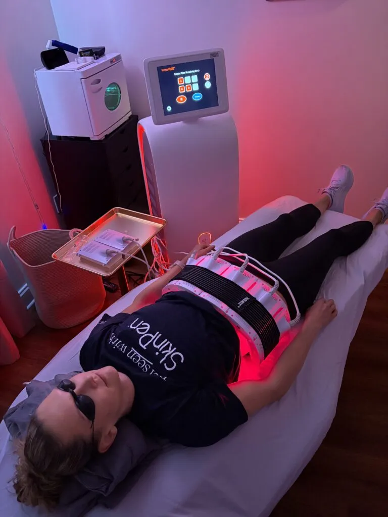 Person receiving red light therapy treatment on abdomen